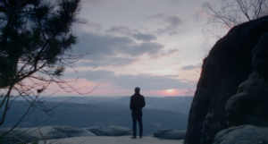 Wide shot of a person standing on a hill facing the sunset. Shot on a Zeiss Super Speed lens.