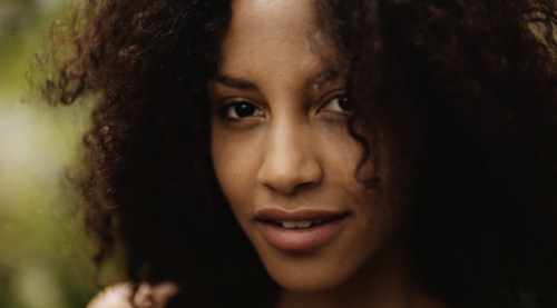 A jung black woman looking into the lens. The lens Used to make this shot was a Zeiss Highspeed lens.