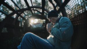 Wide angle shot of a man lighting up a cigarette sitting inside of a greenhouse. Shot on a Zeiss Standard Speed.
