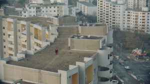 Aerial wide shot of s concrete neighborhood. A woman is walking on the roof. Shot on Cooke Varotal zoom lens.