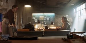 Side shot of two women facing each other in an old building. Sun rays are falling through the window into the hazy room. Unsharp bokeh reveales the characteristics of the Clavius prime lens.